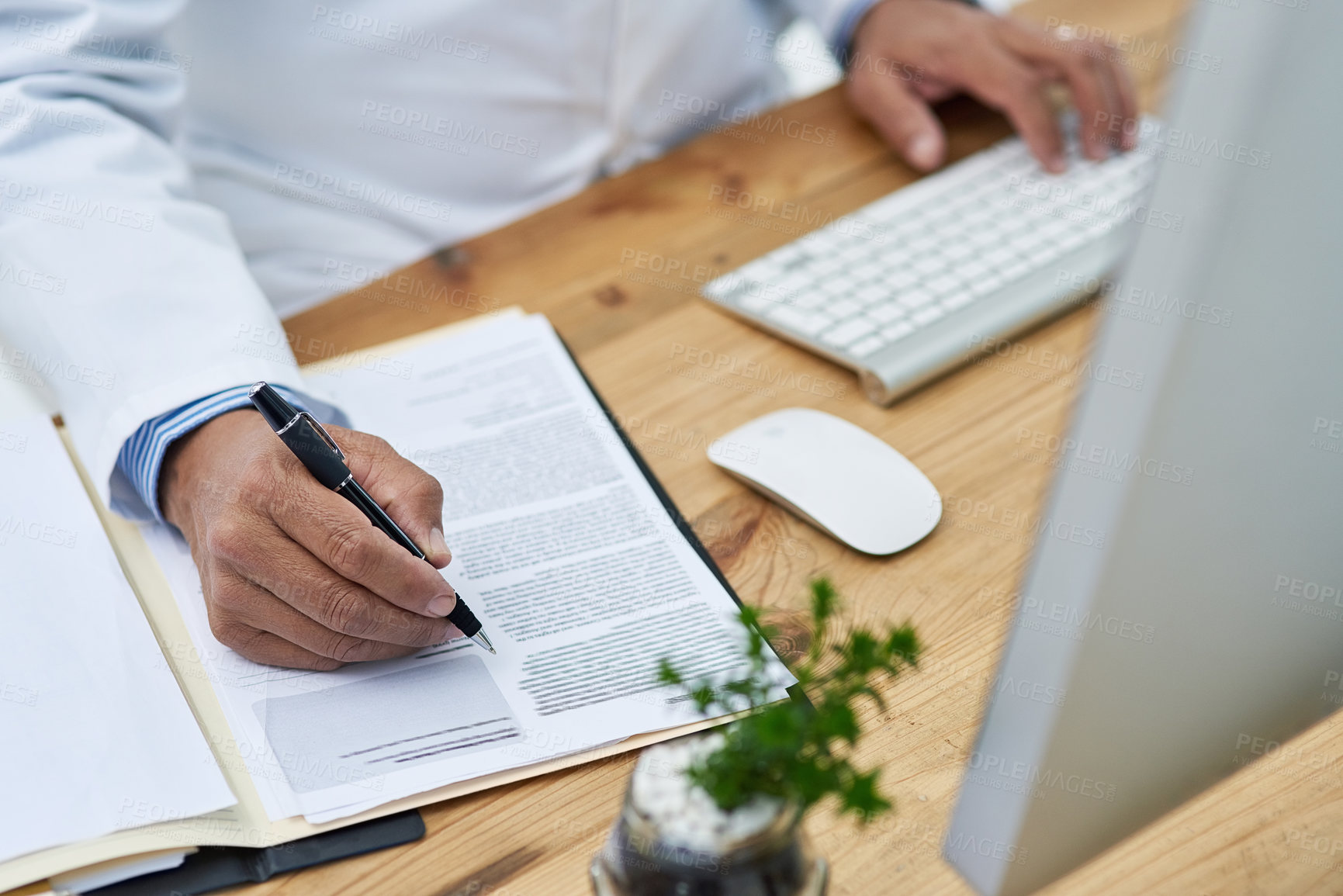 Buy stock photo Closeup shot of a doctor using a computer and making notes in an office