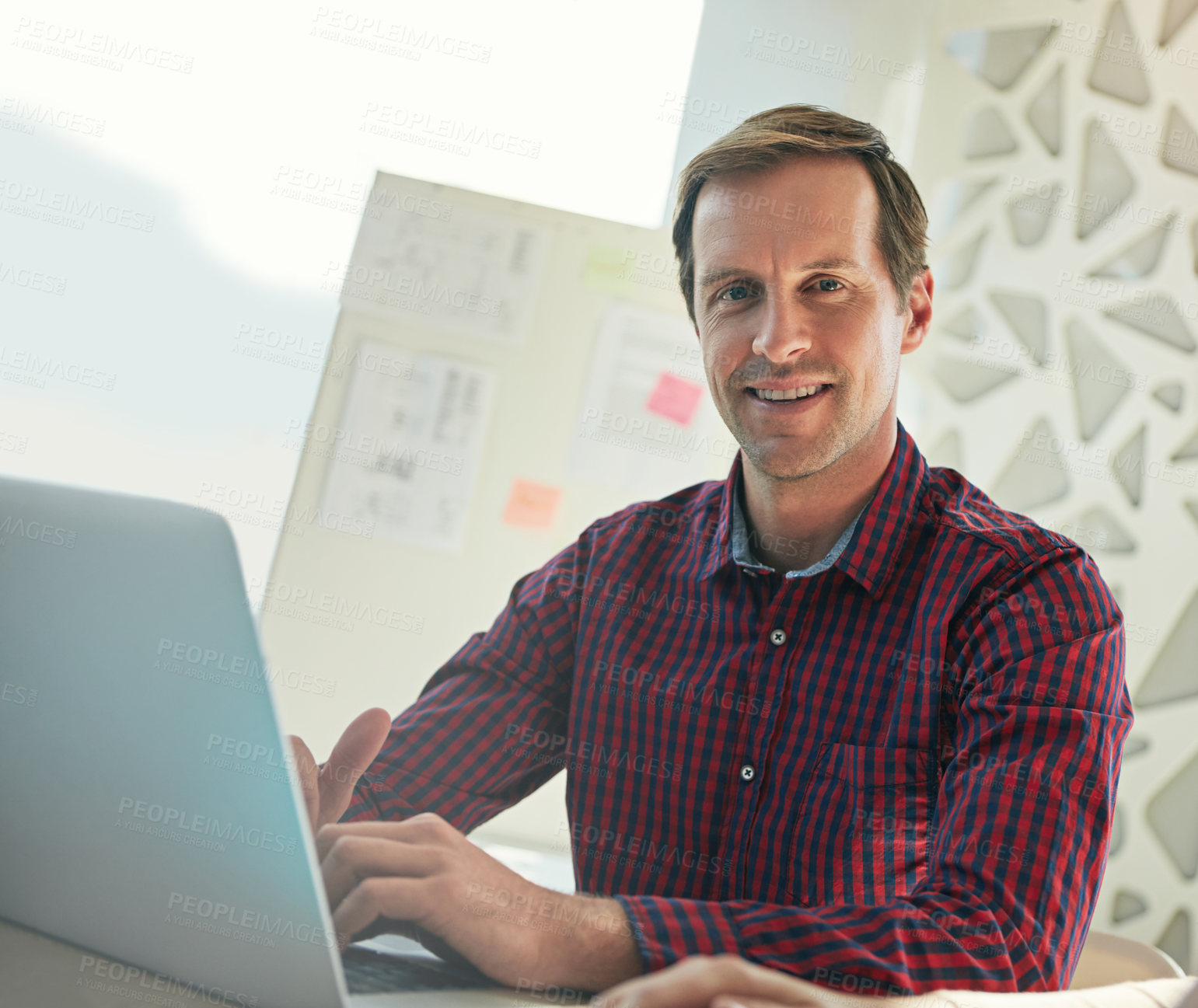 Buy stock photo Cropped shot of a young businessman working on his laptop in the office