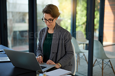 Buy stock photo Cropped shot of a young businesswoman working on a laptop in a modern office