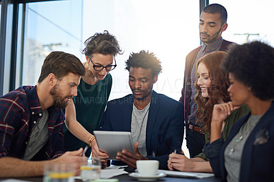Buy stock photo Cropped shot of a group of creatives working together on a digital tablet in a modern office