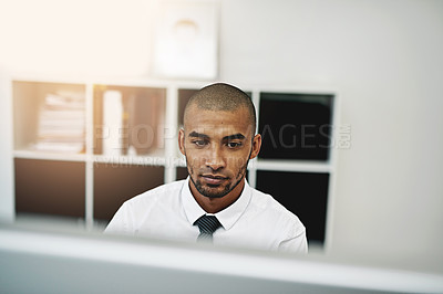 Buy stock photo Shot of a young businessman using a computer at work