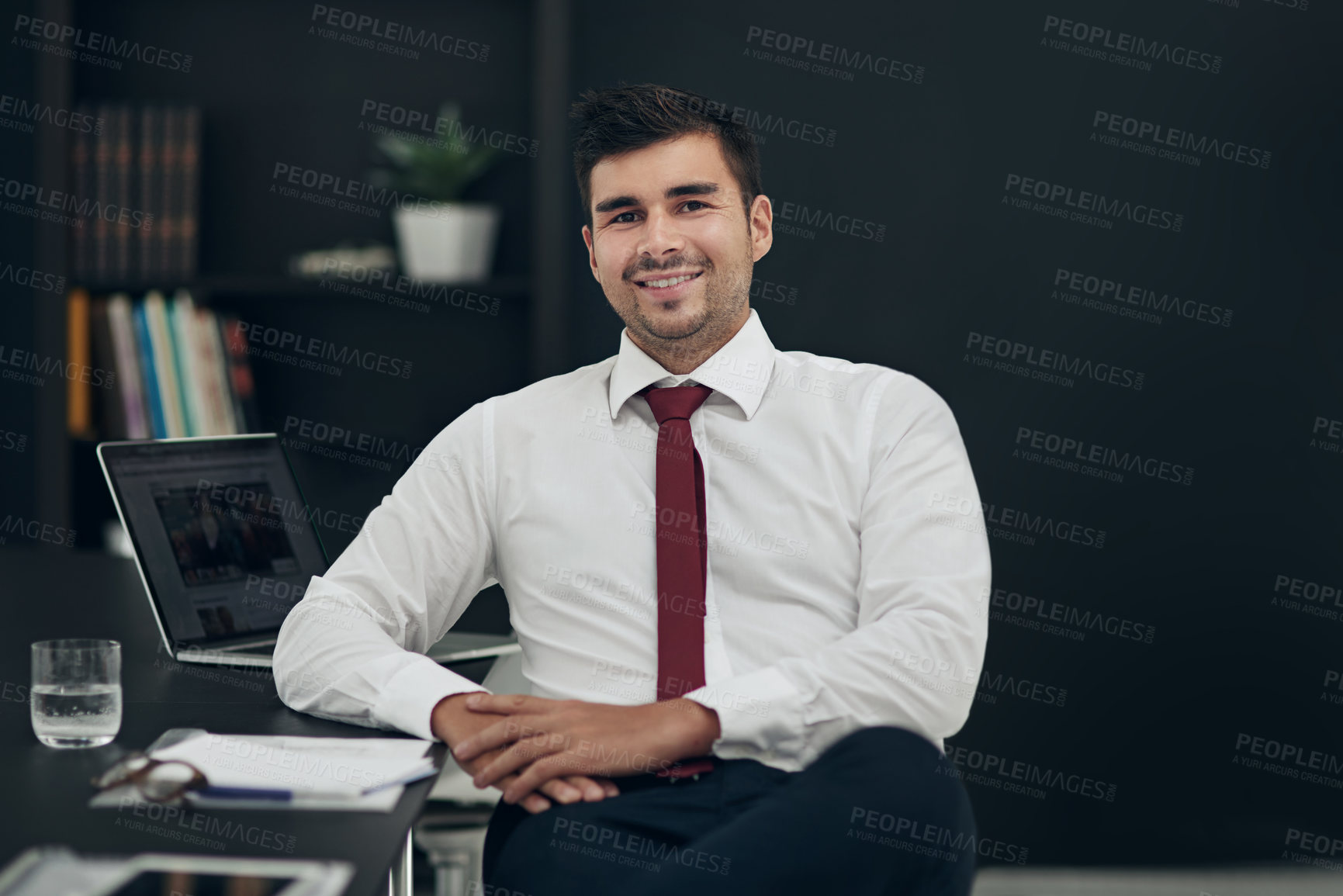 Buy stock photo Cropped portrait of a young businessman sitting in his office