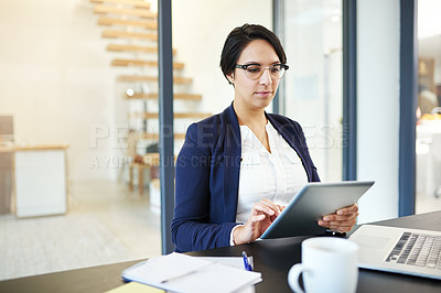 Buy stock photo Cropped shot of a young businesswoman working on a digital tablet in a modern office