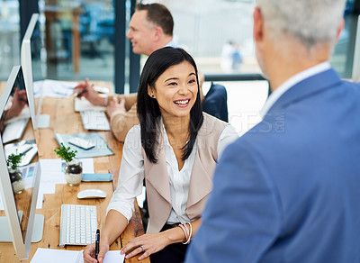 Buy stock photo Cropped shot of two businesspeople working together in the office with a colleague in the background