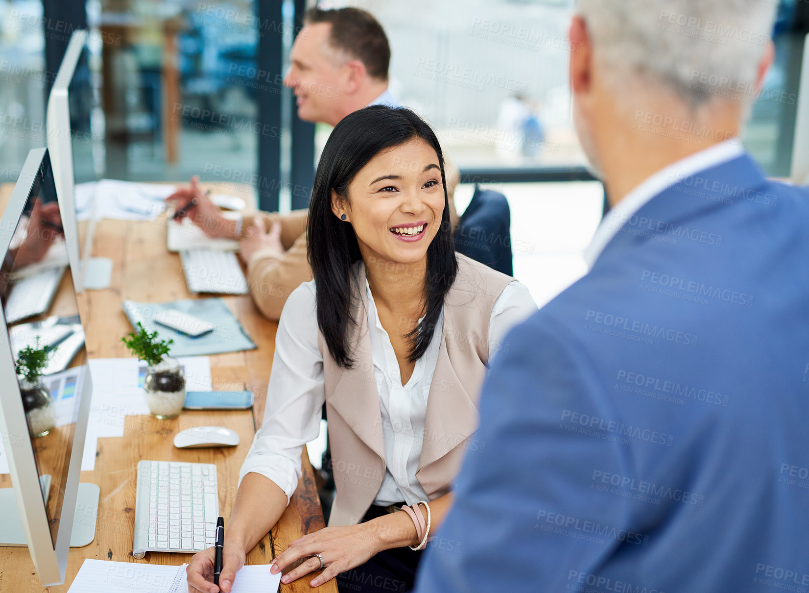 Buy stock photo Cropped shot of two businesspeople working together in the office with a colleague in the background