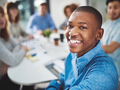 Buy stock photo Cropped portrait of a young businessman looking over his shoulder while sitting in a boardroom with his colleagues