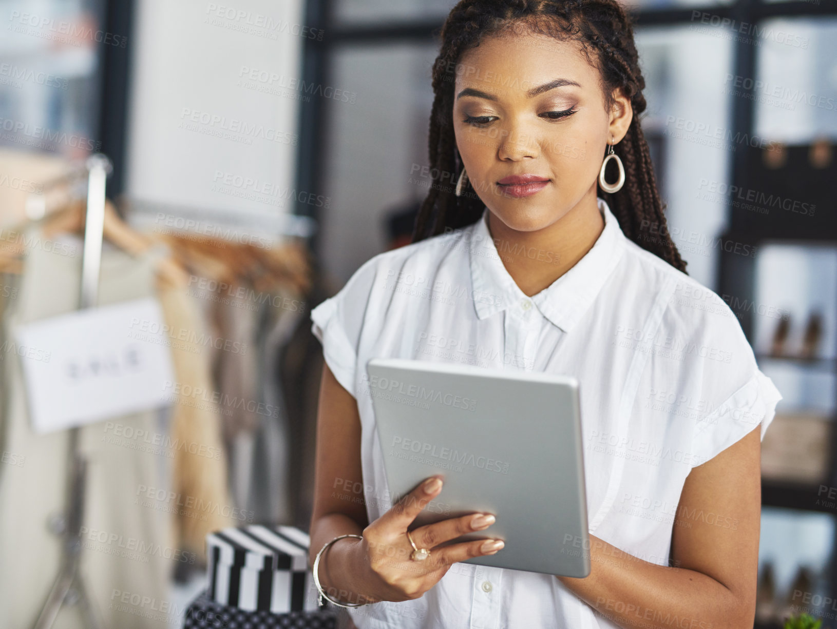 Buy stock photo Cropped shot of a young business owner using her tablet while standing in her store