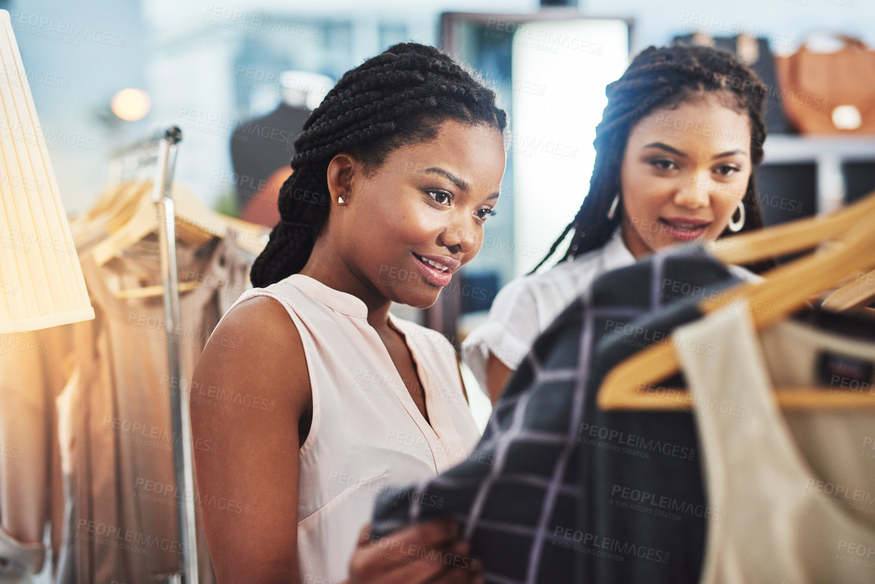 Buy stock photo Cropped shot of two women looking at clothes on a rail in a store