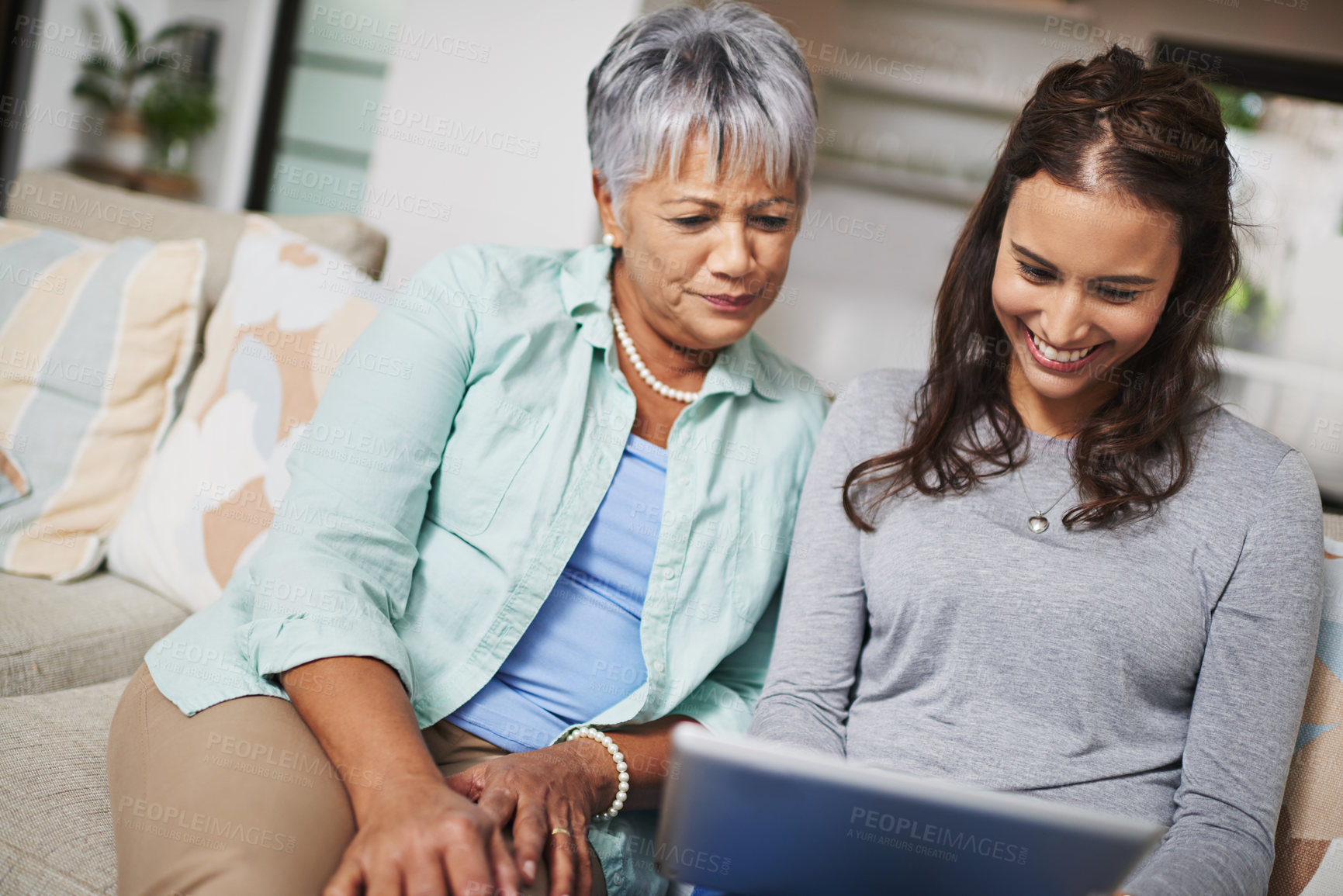 Buy stock photo Happy, tablet and woman teaching senior mother networking on internet, mobile app or website on sofa. Smile, bonding and elderly mom learning digital technology with female person in living room.