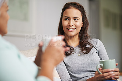 Buy stock photo Shot of a young woman and her mother catching up on the sofa while drinking coffee