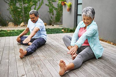 Buy stock photo Shot of a happy older couple practicing yoga together outdoors
