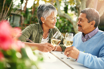 Buy stock photo Shot of a happy older couple sharing a toast over lunch outdoors