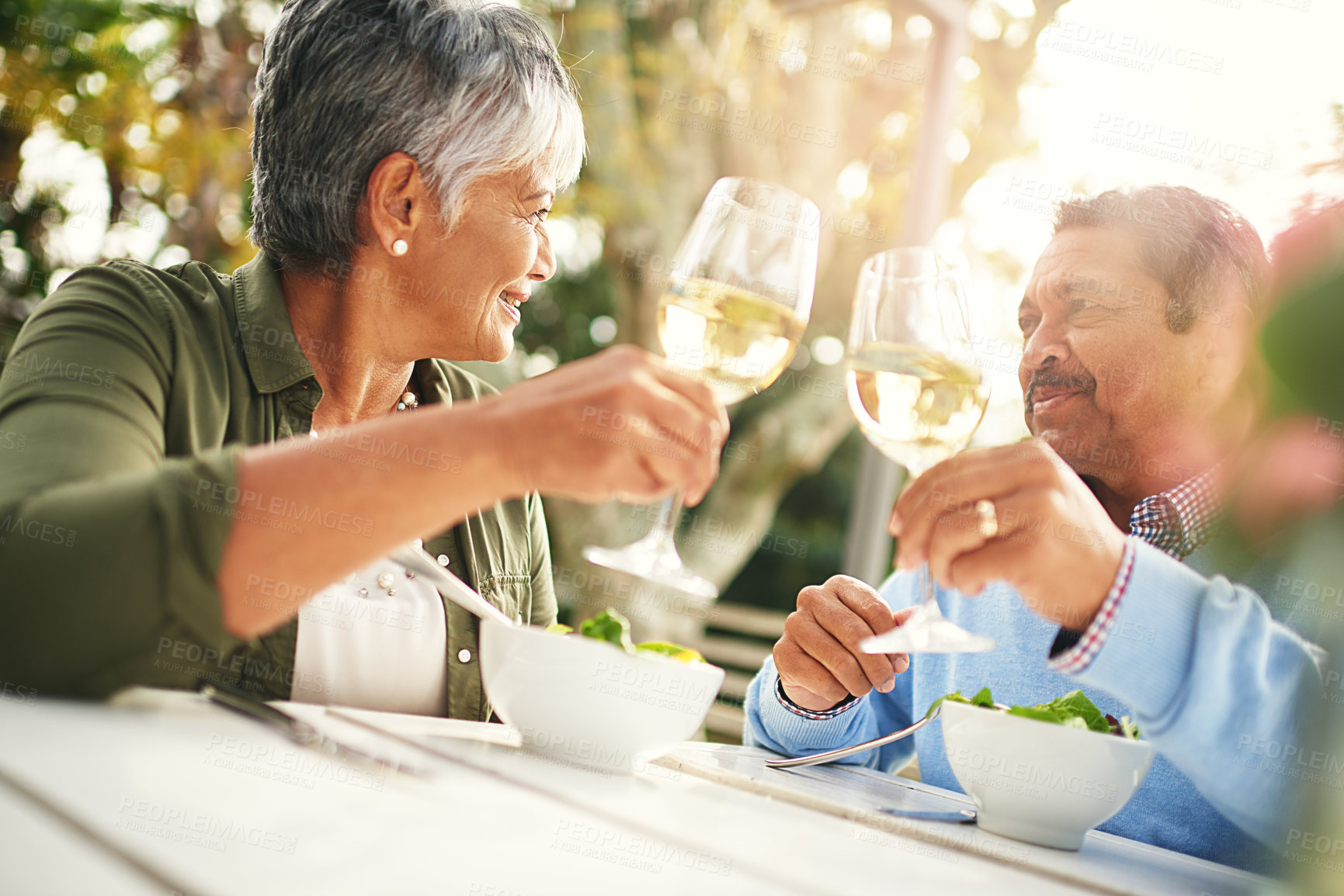 Buy stock photo Shot of a happy older couple sharing a toast over lunch outdoors