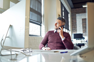 Buy stock photo Shot of a businessman talking on his cellphone while sitting at his desk