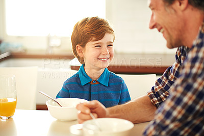 Buy stock photo Cropped shot of a father and son enjoying breakfast together at home