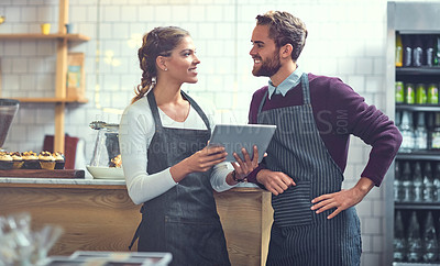 Buy stock photo Shot of a young man and woman using a digital tablet together in their store