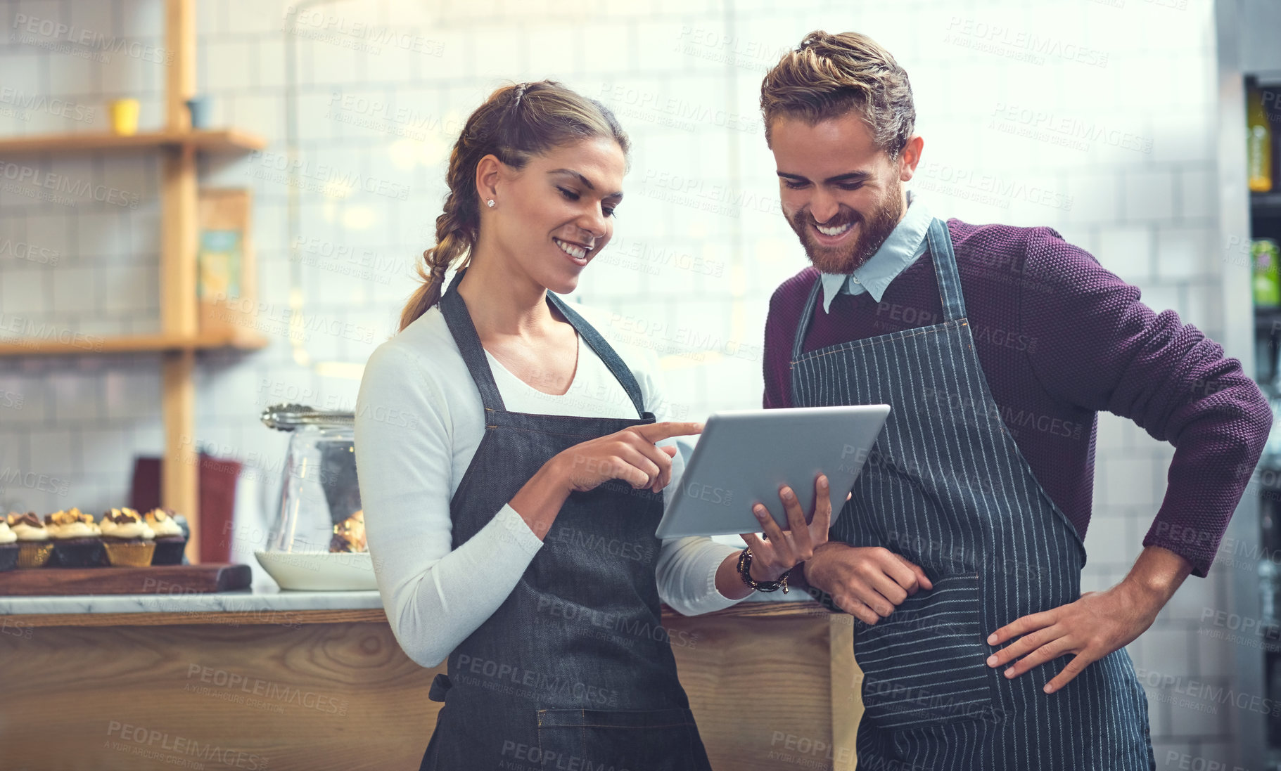 Buy stock photo Shot of a young man and woman using a digital tablet together in their store