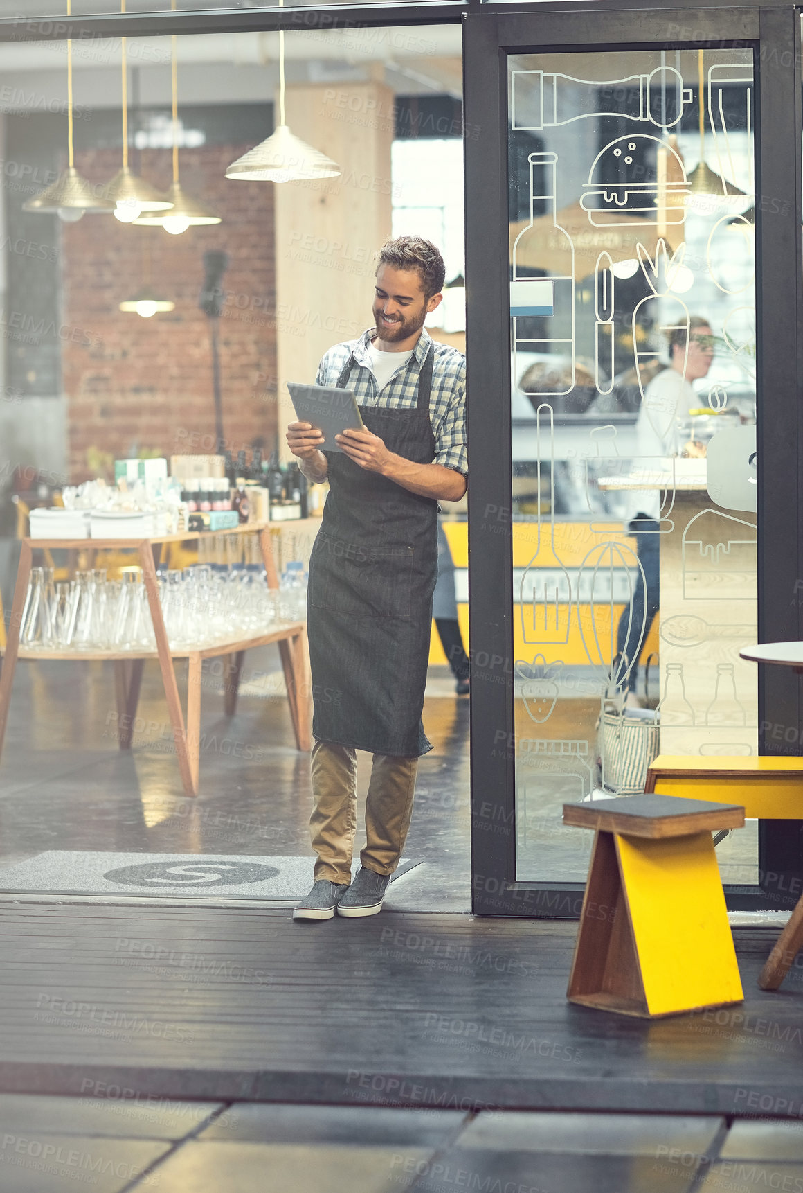 Buy stock photo Shot of a young man using a digital tablet in the store that he works at