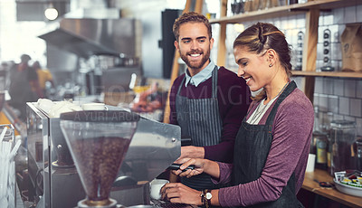 Buy stock photo Shot of two young baristas operating a coffee machine together at a cafe