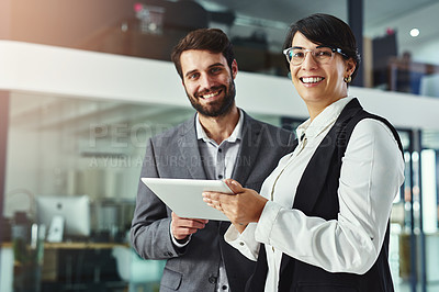 Buy stock photo Portrait of two colleagues working together on a digital tablet in a modern office