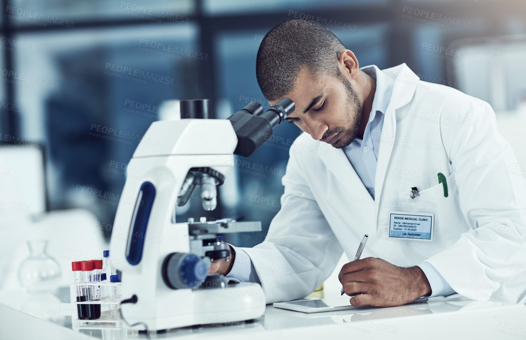 Buy stock photo Serious male scientist writing on a tablet for an online phd research paper in a lab. Laboratory worker working on health data for a science journal. Medical professional analyzing test results
