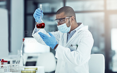 Buy stock photo Shot of a young scientist conducting an experiment in his lab