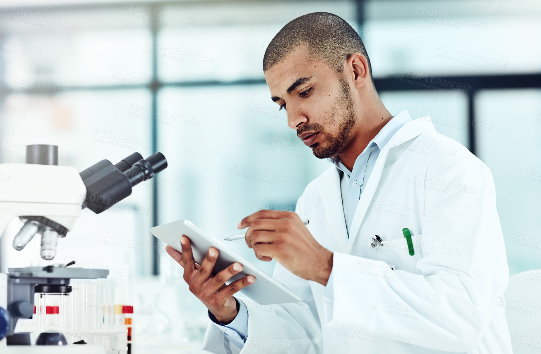 Buy stock photo Serious male scientist working on a tablet reviewing an online phd publication in a lab. Laboratory worker updating health data for a science journal. Medical professional document clinical trial