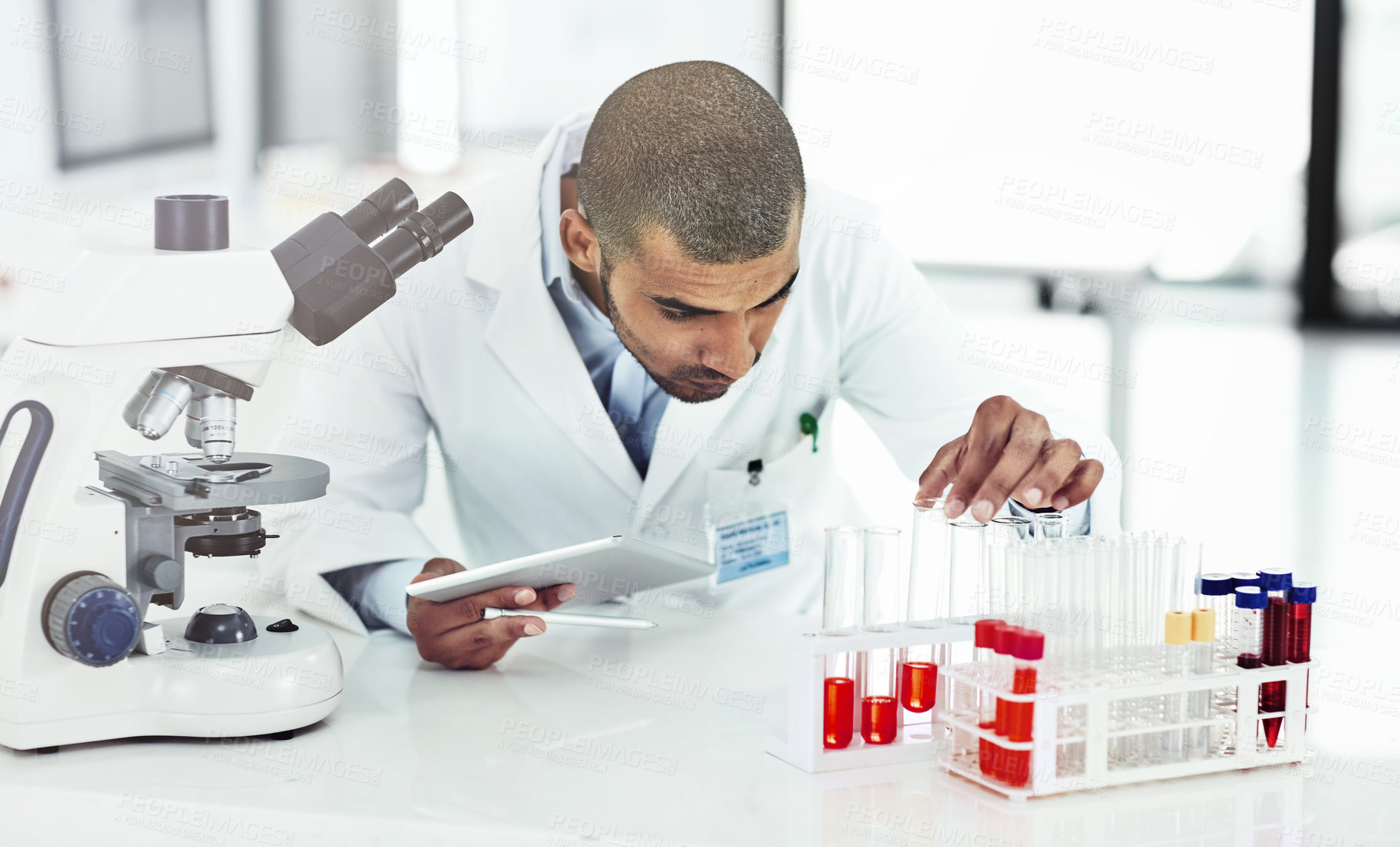 Buy stock photo Shot of a male scientist examining a test tube filled with blood