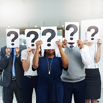 Buy stock photo Shot of a group of businesspeople holding placards with question marks in front of their faces