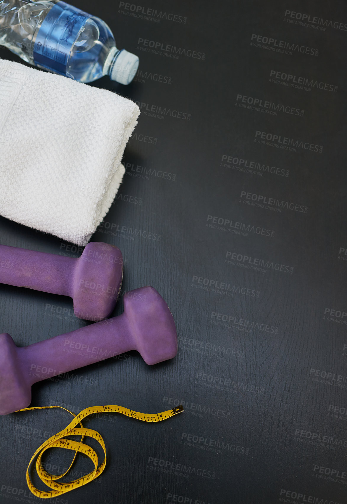 Buy stock photo High angle shot of a water bottle, towel, weights and tape measure against a black background