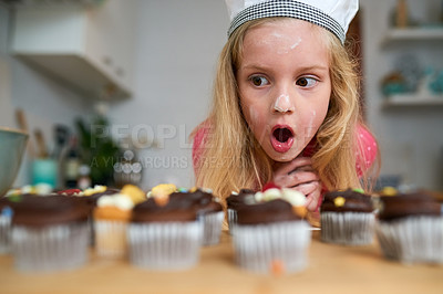 Buy stock photo Shot of a surprised little girl looking at cupcakes she baked at home