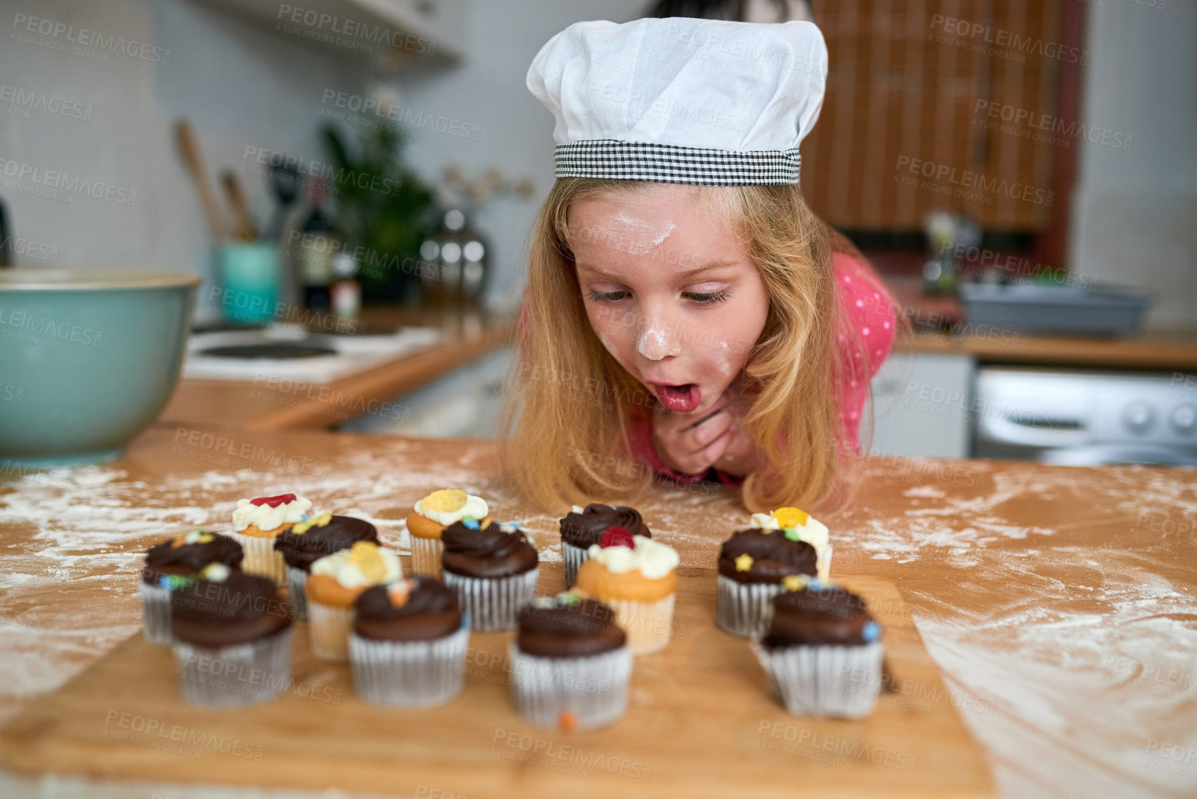 Buy stock photo Excited, child and baking cupcake in kitchen on table with hungry girl with wow face in home. Happy, surprise and cooking chocolate sweets, food or learning to bake dessert in holiday or vacation