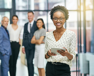 Buy stock photo Portrait of a young businesswoman holding a digital tablet with her colleagues in the background