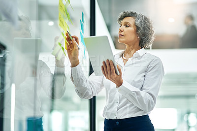 Buy stock photo Cropped shot of a mature businesswoman writing notes on a glass wall in a modern office
