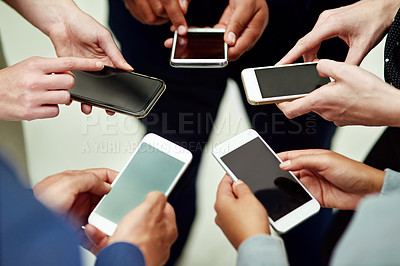 Buy stock photo Cropped shot of a group of unidentifiable businesspeople using their smartphones in a huddle