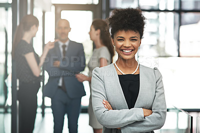 Buy stock photo Portrait of a confident young businesswoman standing in a modern office with colleagues in the background