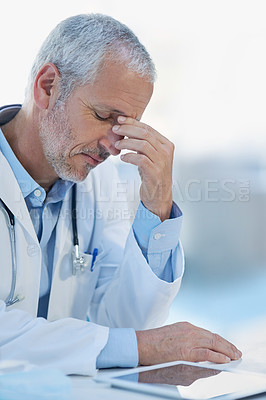 Buy stock photo Cropped shot of a mature doctor feeling stressed out at work