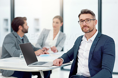 Buy stock photo Portrait of a businessman sitting in a boardroom meeting with colleagues in the background