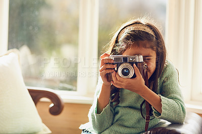 Buy stock photo Shot of a little girl taking pictures with a vintage camera at home