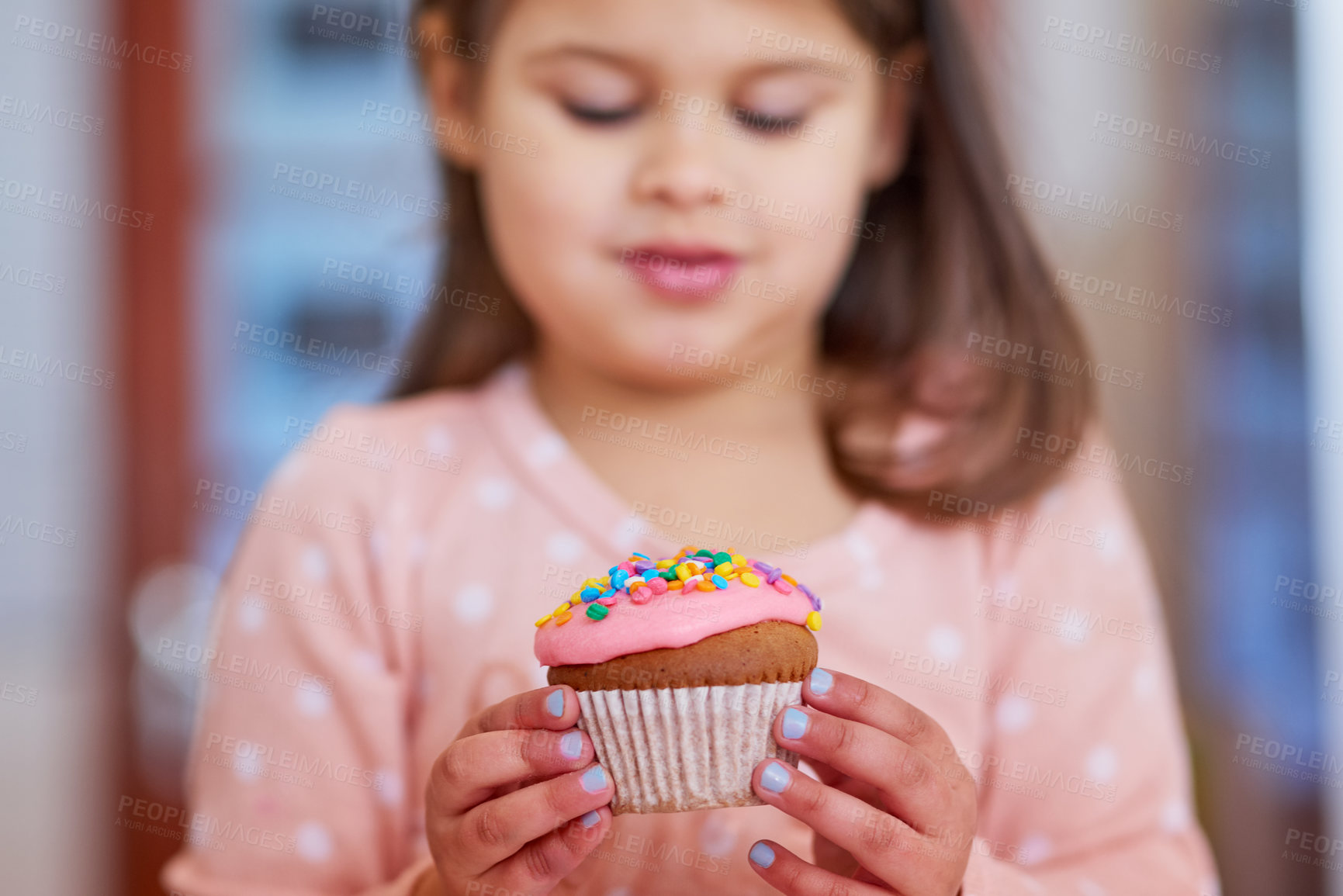 Buy stock photo Cropped shot of a little girl looking at a cupcake in her hands