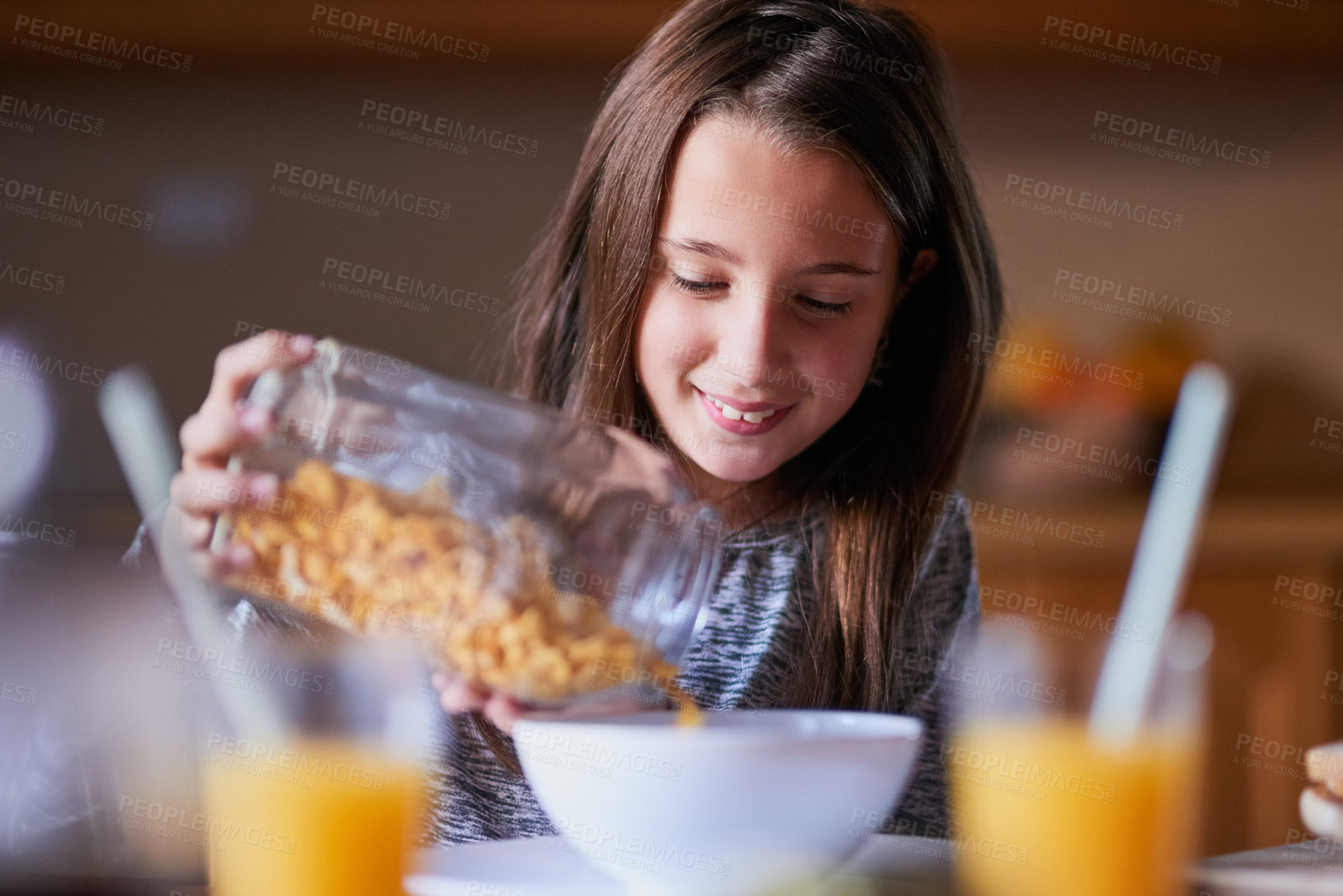 Buy stock photo Cropped shot of a young girl pouring cereal into a bowl by herself