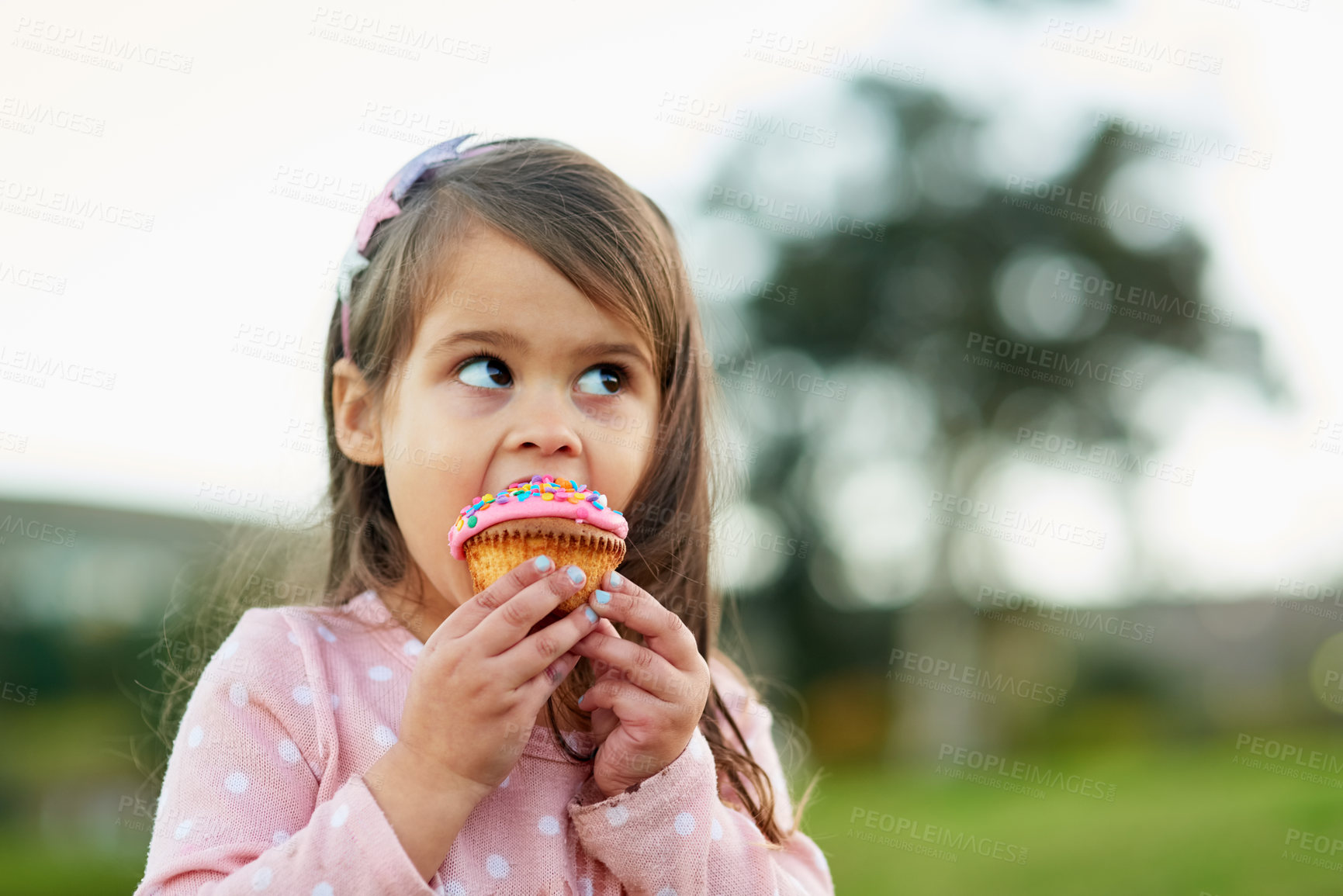 Buy stock photo Cropped shot of a little girl enjoying a cupcake outside