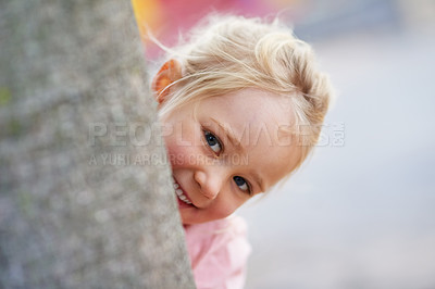 Buy stock photo Portrait of a cute little girl peeking out from behind a tree