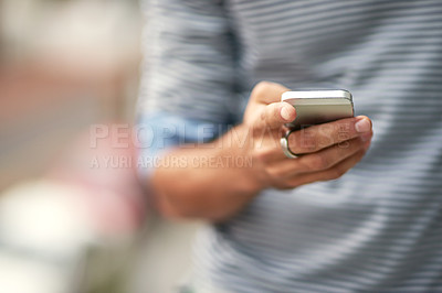 Buy stock photo Closeup shot of a young man texting on a cellphone outside