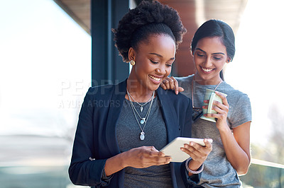 Buy stock photo Shot of two young colleagues using a digital tablet together at work