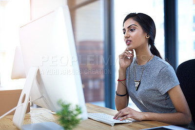 Buy stock photo Shot of a focused young businesswoman using a computer at her work desk