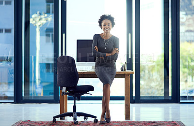 Buy stock photo Portrait of a confident young businesswoman leaning against a desk at work