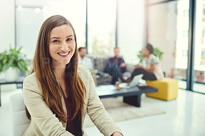 Buy stock photo Portrait of a confident young businesswoman sitting in an office with colleagues in the background