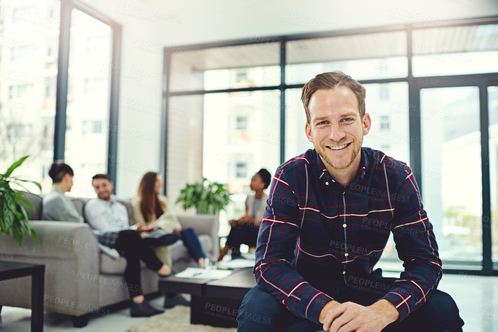 Buy stock photo Portrait of a confident businessman sitting in an office with colleagues in the background