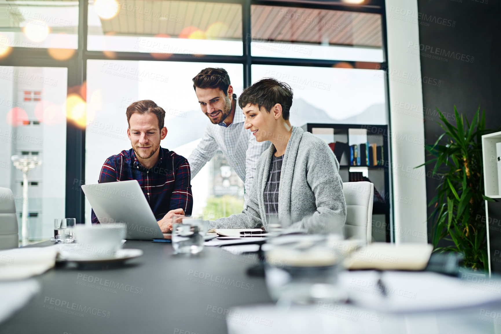 Buy stock photo Cropped shot of a group of businesspeople working together on a laptop in a modern office